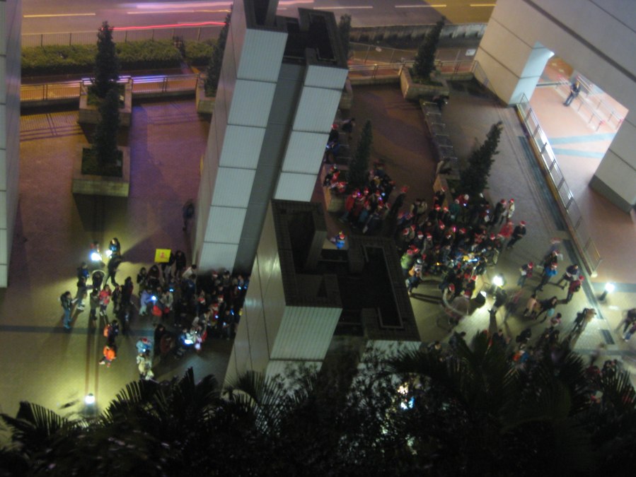 xmas eve outside Hang Hau MTR [view from our balcony] - the city is full of carol singing groups battling for supremacy, the one with the brass band seems likely to win