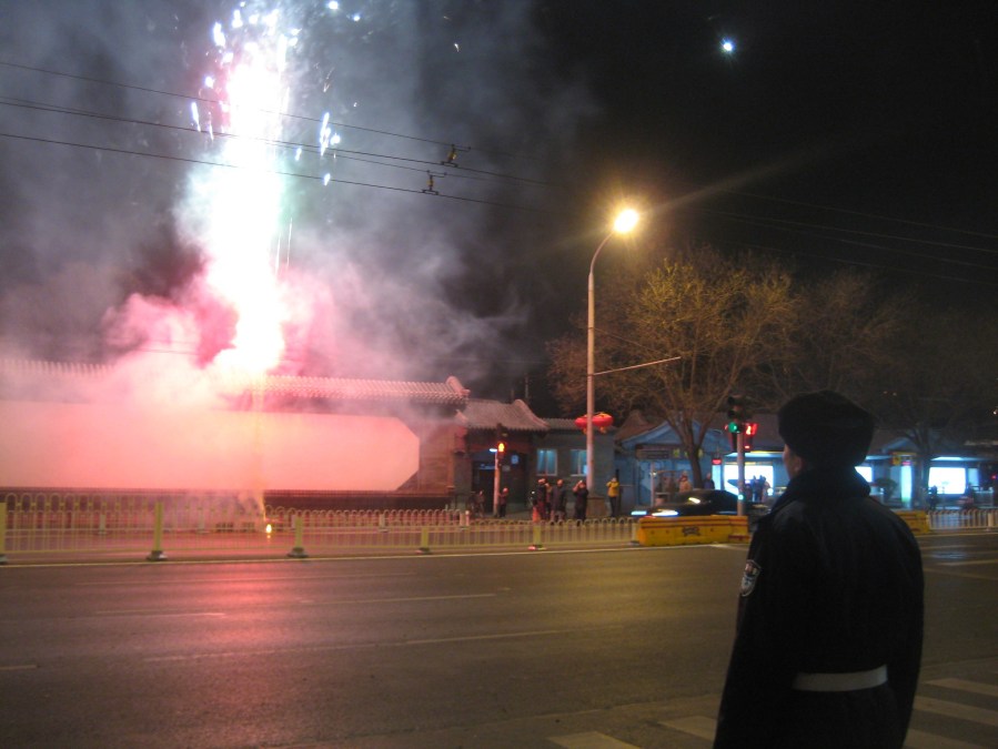 one of the security guards observes fireworks across the road from our apartment on the street 